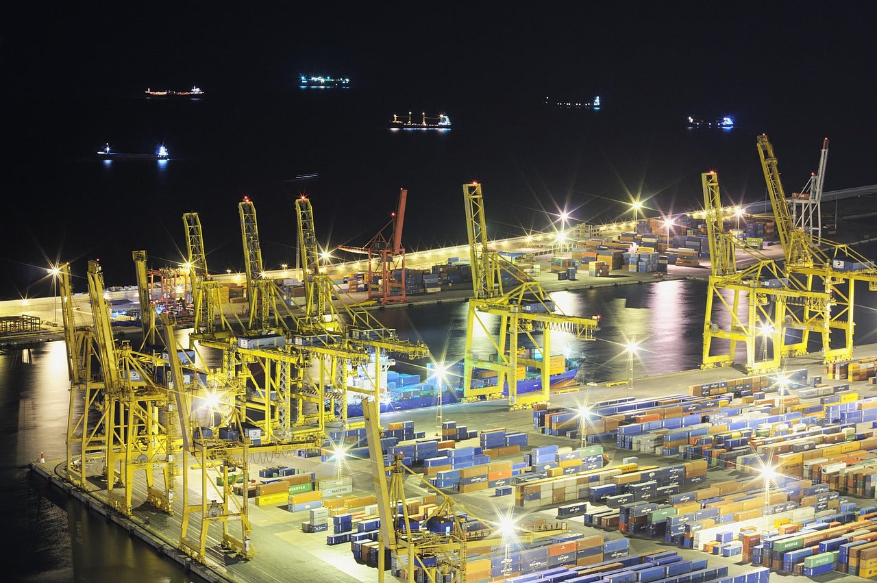 📦 Port logístic de Barcelona de nit, amb grues il·luminades i vaixells de càrrega al fons.